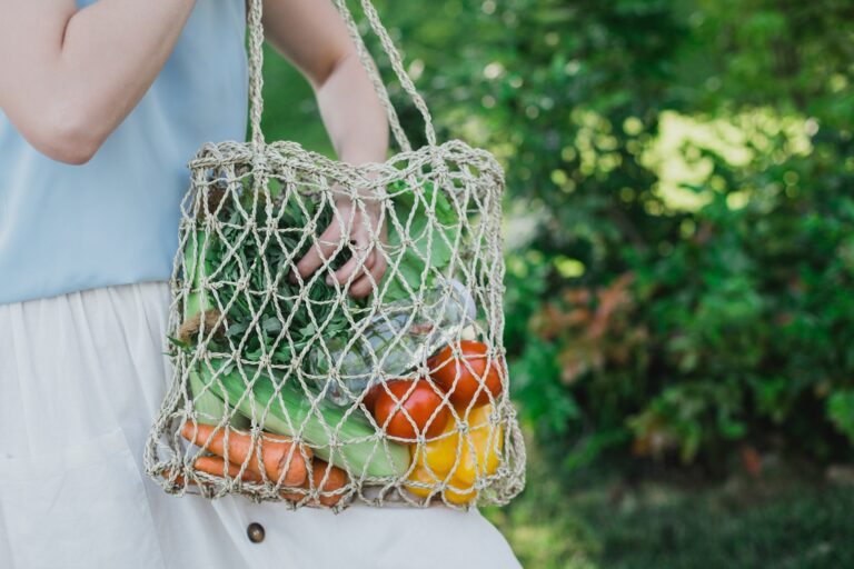 Young woman standing with eco friendly shopping bag with fresh vegetables without plastic packing