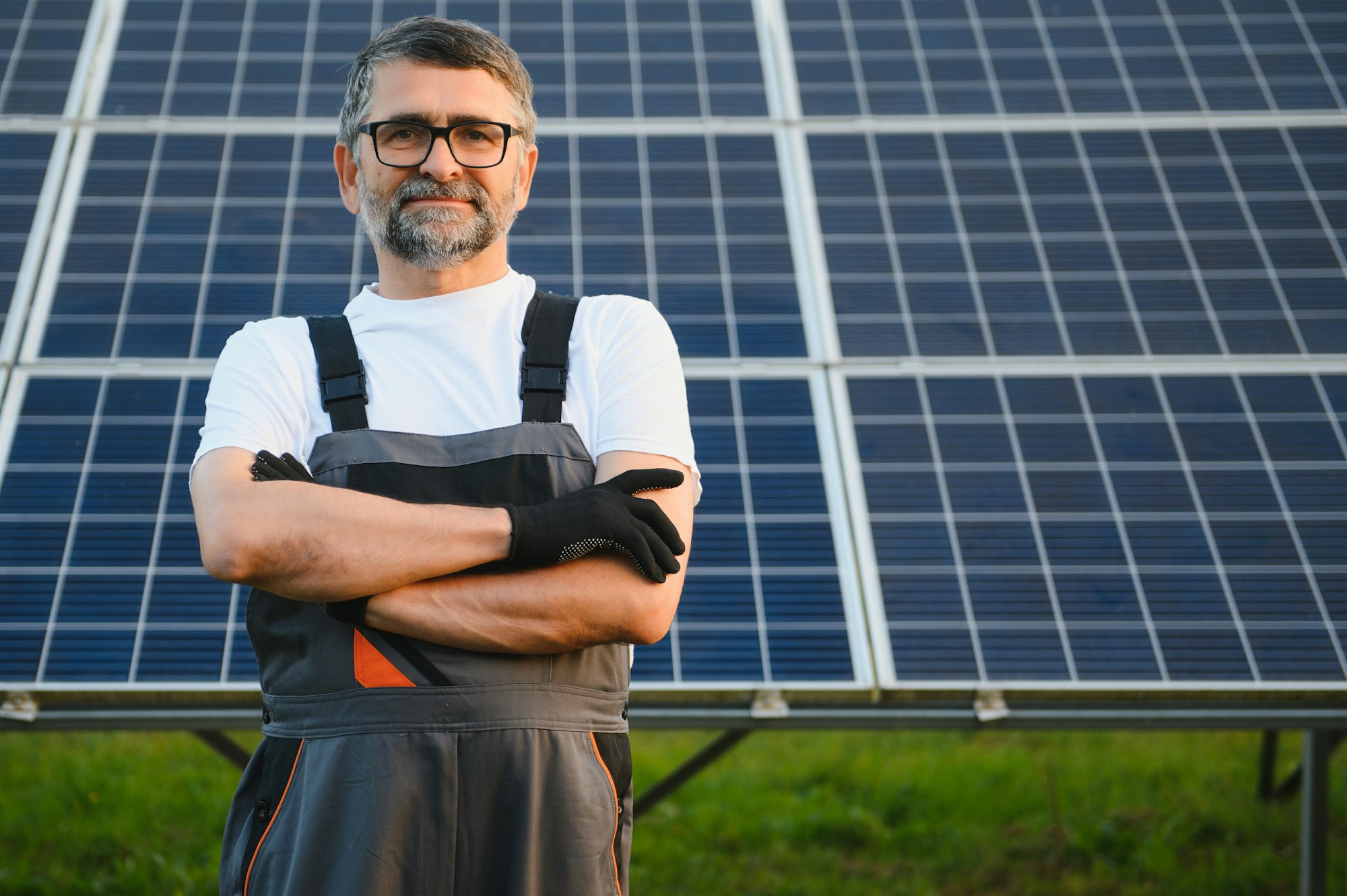 Portrait of senior worker in uniform standing near solar panels